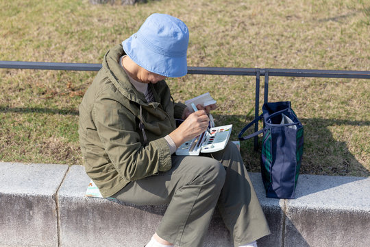 Woman with blue hat drawing on a bridge