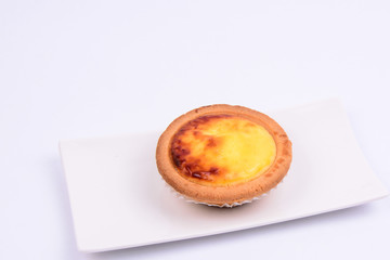 A whole cheese tart in a white ceramic plate isolated on white background.