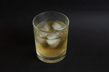 A glass of whisky with ice cubes on black color table background. Alcoholism. Party. 