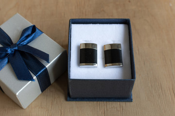 Pair of cufflinks in a gift box on wooden background. Fashion gift for man.
