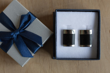 Pair of cufflinks in a gift box on wooden background. Fashion gift for man.