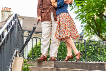 Montmartre, retro dressed lovers on a romantic staircase, with an umbrella, rainy day, legs 