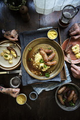 Tattooed couple having sausage and beers for dinner
