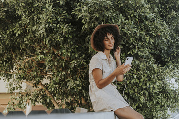 Beautiful woman listening to music in a botanical garden