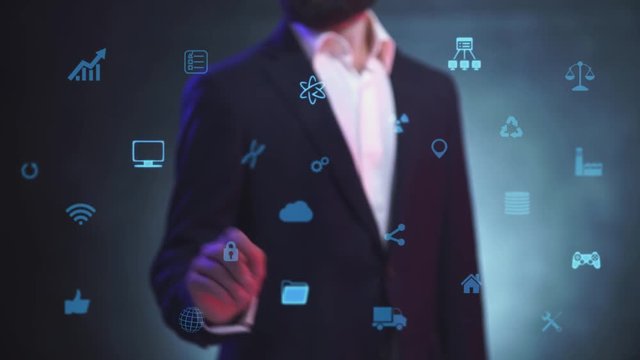 Businessman in suit working and manages on hologram HUD interface, touching on visual screen with neon icons, chooses - Blockchain icon in interface.