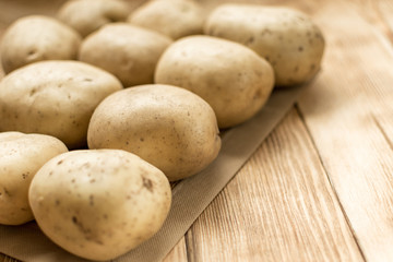 Raw potato tubers on a wooden background.