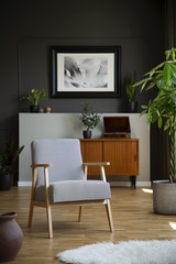 Retro armchair and tree in a living room interior with a cabinet and painting in the background