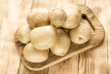 Raw potato tubers on a wooden background.