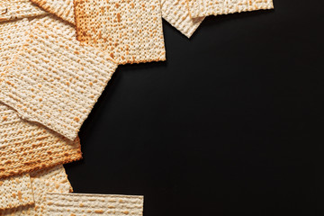 A photo of matzah or matza pieces  on black background. Matzah for the Jewish Passover holidays. Place for text, copy space