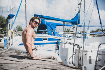 Sexy bearded man standing on the yacht club. Guy on a sailing boat. Handsome man enjoying life,...