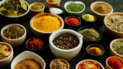 From above view of many little bowls with different kinds of spices laid on wooden background