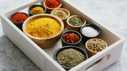 From above of small wooden tray box with composed bowls of various aromatic spices on table