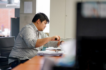 Employees man are preparing documents in the office. With Binding Machine