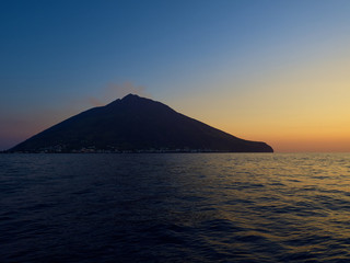 Naklejka na ściany i meble Shooting the volcano at sunset from the boat