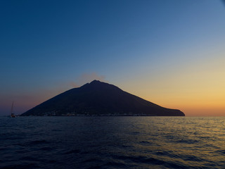 Naklejka na ściany i meble Shooting the volcano at sunset from the boat