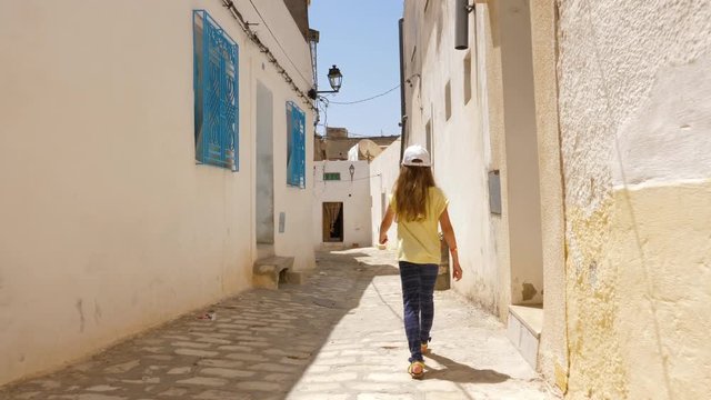 Girl walking on narrow street in old town, rear view