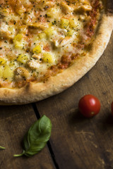 A pizza with pineapple and chicken on a vintage wood surface