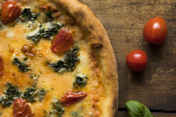 A pizza with dried tomatoes cheese and basil leaves