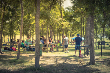 Blurred large group of friend, family members enjoy barbecue on lakeside area. Outdoor camping at...