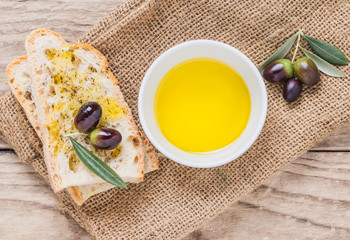 Olive oil and fresh branch of olives on wooden table and piece of bread.Testing fresh extra virgin...
