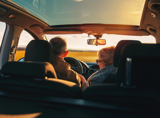 Elderly loving couple traveling in car on vacation.