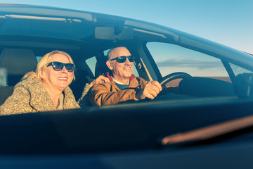 Elderly loving couple traveling in car on vacation.
