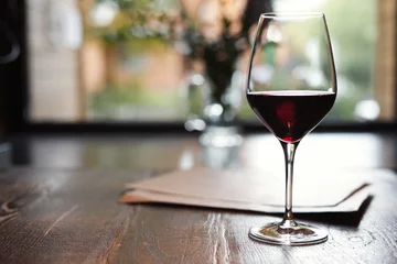 Photo sur Plexiglas Vin A Glass of red wine in restaurant or cafe on wooden table in front of window, romantic date, lunch relaxation