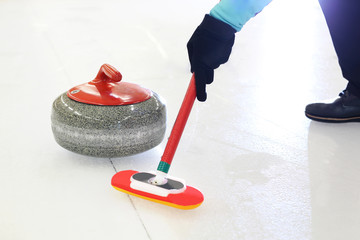 Rozgrywki curlingowe.  Zawodnik szczotkuje lód kierując kamień do domu - obrazy, fototapety, plakaty