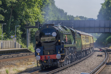 Clan Line. A Merchant Navy Class Steam  locomotive speeds through Farnborough Station , Hampshire on 5th July, 2017.  with The Bournemouth Belle