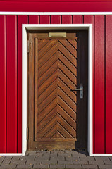 Scandinavian-style bright red and white facade with brown wooden herringbone door