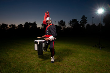 Cool portrait of musician in uniform with atmospheric light on a green grass field at sunset