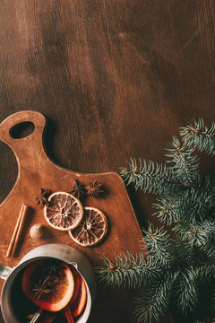 top view of homemade mulled wine with spices on cutting board on wooden background with pine branch