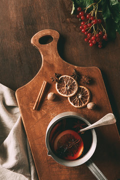top view of hot mulled wine with spices and viburnum berries on wooden background