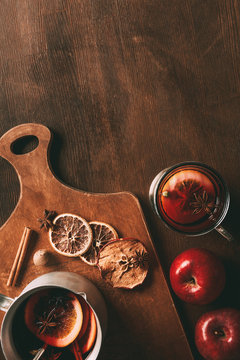 top view of homemade mulled wine with spices and apples on cutting board on wooden background