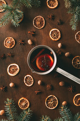 Fototapeta na wymiar top view of mulled wine with dried orange slices and spices on wooden background with fir branches