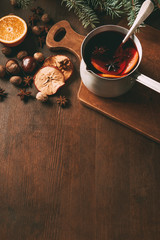 hot spiced wine in saucepan with christmas spices on wooden background