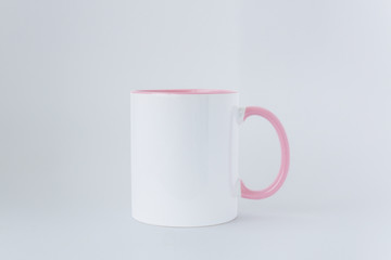 The white mug with  pink handle on a grey background. 