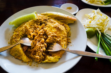 Egg wrapped pad thai on a plate in restaurant