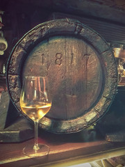 glass of old white wine with barrel. Ancient alcoholic beverage with a vintage wooden barrel