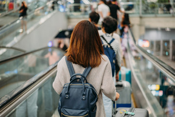Young woman holding suitcase or baggage with backpack in the international airport.
