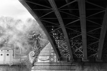 Under the Czech bridge in Prague, a foggy morning with a female statue with a  torch showing the way