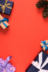 Fototapeta premium top view of christmas presents and pine cones on red background
