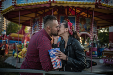 young cute  couple in amusement  park kissing 