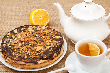 Cup of tea, porcelain teapot and homemade chocolate puff cake on desk