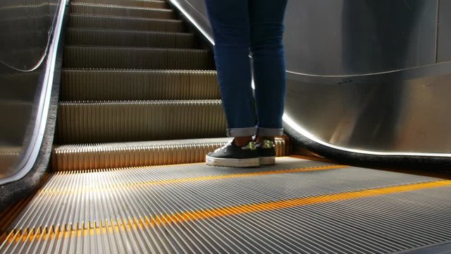 Close shot of electric escalator with parts of a person going upwards 