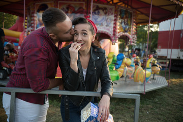 young cute  couple in amusement  park eating pop corns 