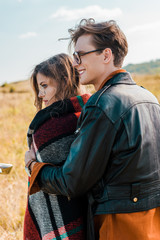 young couple in glasses looking away on rural meadow