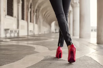 Muurstickers Woman walking in black pants and red high heels © Kaspars Grinvalds