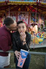 young cute  couple in amusement  park eating pop corns 