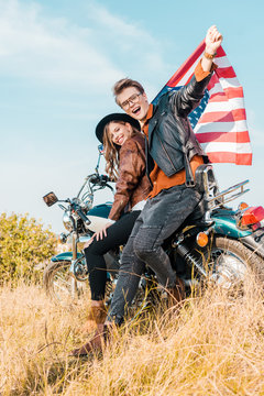 happy couple with american flag sitting on meadow, independence day concept © LIGHTFIELD STUDIOS